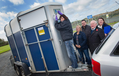 PSNI Crime Prevention Officer, Dolores Coulter, puts a unique identification mark on the trailer of David and Amanda Revie, who are pictured with Alderman Ronnie Ferguson, Chair of the Ards Policing and Community Safety Partnership (PCSP) and Nicola Dorrian, PCSP Officer. 