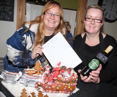 Karen McVeigh, manager of Lowden Guitars at the Down Business Centre is  pictured with Lisa Davey at Mange Tout French delicatessen with the gingerbread Christmas cake being raffled to support the Husky Haven.
