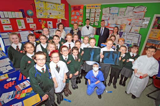 Fionnoula Magee (Haematologist), Agnes Monan, (Acting Principal), Michael McGarrity P5-7 Teacher, Councillor Colin McGrath, and Carina Fitzsimons (Classroom Assistant) with pipils who participated in the NHS project at St Malachy's Primary School in Kilclief.