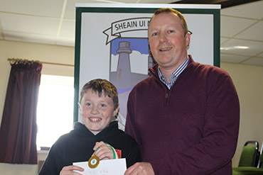 5K winner shows Mackenzie Murray receive his prize from the Cloughey Centra Manager.